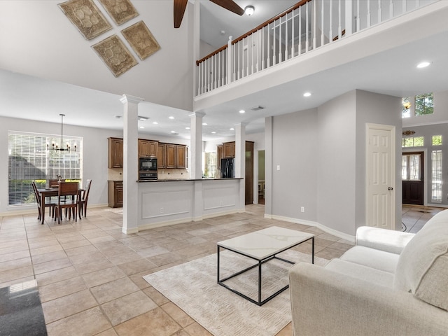 living area with decorative columns, plenty of natural light, ceiling fan, recessed lighting, and a towering ceiling