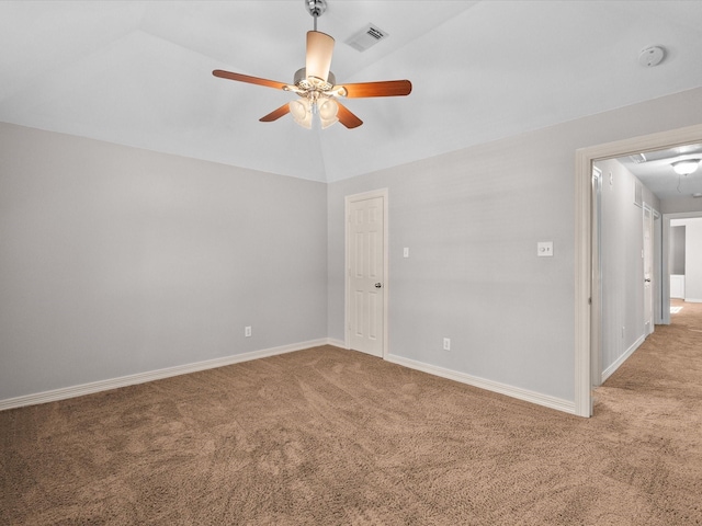 carpeted empty room featuring ceiling fan, attic access, vaulted ceiling, and baseboards