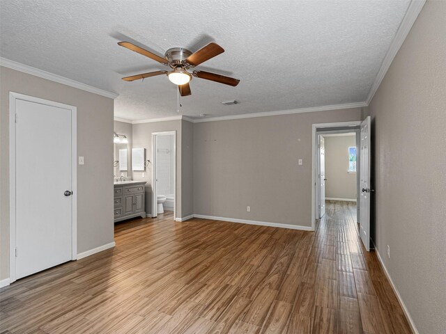 1726 Meadow Green Dr, Missouri City, TX 77489 - unfurnished bedroom featuring wood finished floors, a textured ceiling, a sink, baseboards, and ornamental molding