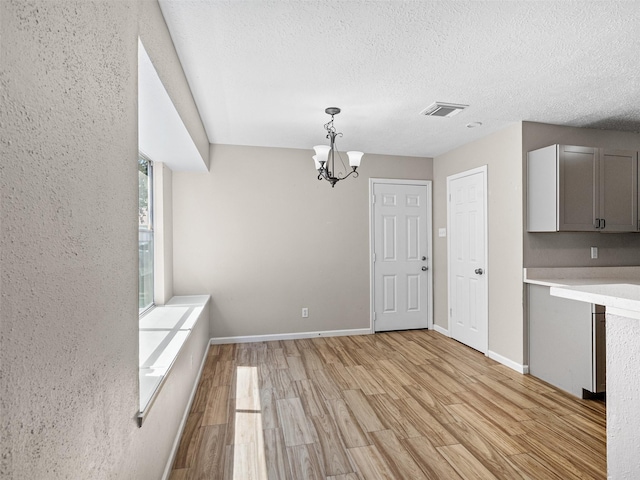1726 Meadow Green Dr, Missouri City, TX 77489 - unfurnished dining area featuring light wood-style floors, a chandelier, a textured ceiling, and baseboards