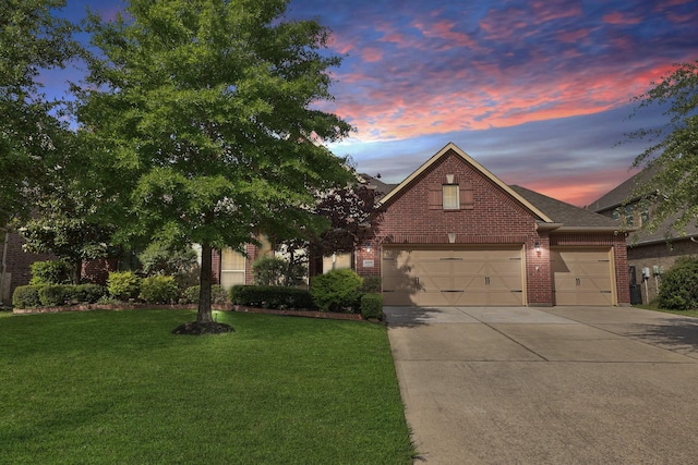 view of front of house with brick siding, driveway, a lawn, and a shingled roof
