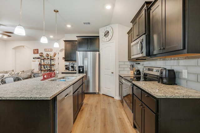 2065 Chief St, Bryan, TX 77807 - kitchen featuring stainless steel appliances, a sink, arched walkways, light wood-style flooring, and tasteful backsplash