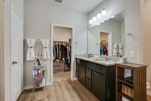 2065 Chief St, Bryan, TX 77807 - bathroom featuring wood finished floors, double vanity, a spacious closet, and baseboards