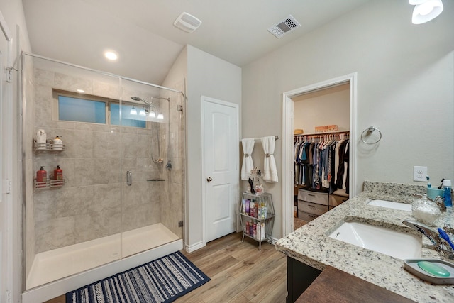 2065 Chief St, Bryan, TX 77807 - bathroom with a stall shower, wood finished floors, double vanity, a walk in closet, and recessed lighting