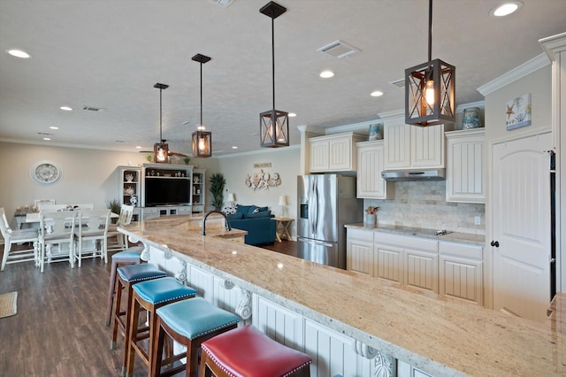 3025 Carioca Ct, Crystal Beach, TX 77650 - kitchen featuring under cabinet range hood, crown molding, stainless steel fridge with ice dispenser, light stone countertops, and decorative backsplash