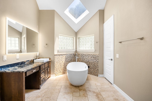 2911 S Saddlebrook Ln, Katy, TX 77494 - bathroom with stone tile floors, a freestanding tub, double vanity, plenty of natural light, and high vaulted ceiling