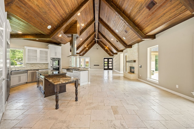 2911 S Saddlebrook Ln, Katy, TX 77494 - kitchen featuring stone tile flooring, dishwasher, a fireplace, a wooden ceiling with exposed beams, and open floor plan