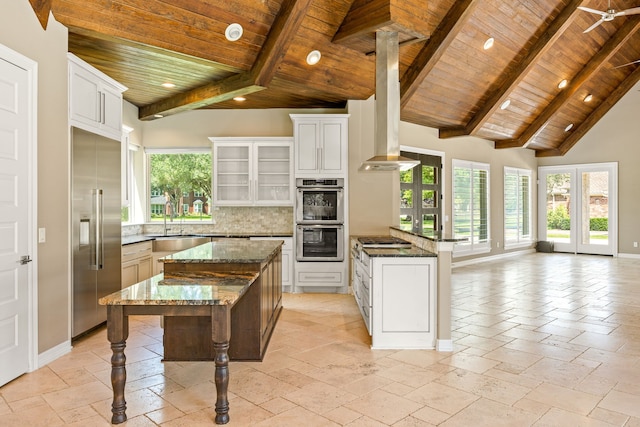 2911 S Saddlebrook Ln, Katy, TX 77494 - kitchen featuring a wood ceiling with exposed beams, stainless steel appliances, a peninsula, decorative backsplash, and a breakfast bar area