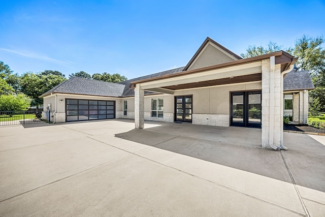 2911 S Saddlebrook Ln, Katy, TX 77494 - view of front of home featuring french doors, driveway, stone siding, a garage, and stucco siding