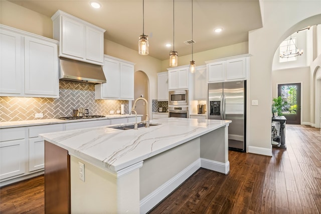 9811 Mount Shasta, Missouri City, TX 77459 - kitchen featuring appliances with stainless steel finishes, arched walkways, under cabinet range hood, a center island with sink, and white cabinets