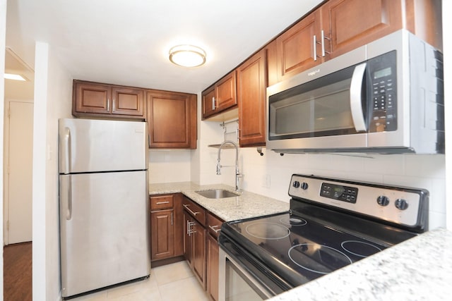 2016 Main St Unit 1208, Houston, TX 77002 - kitchen with stainless steel appliances, a sink, brown cabinets, light stone countertops, and light tile patterned flooring