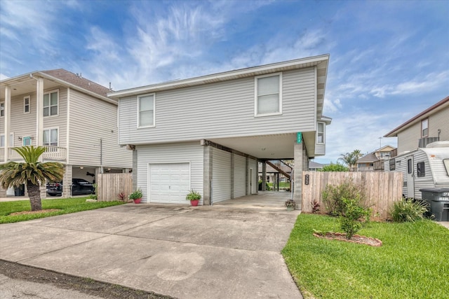 raised beach house with a carport, an attached garage, driveway, and fence