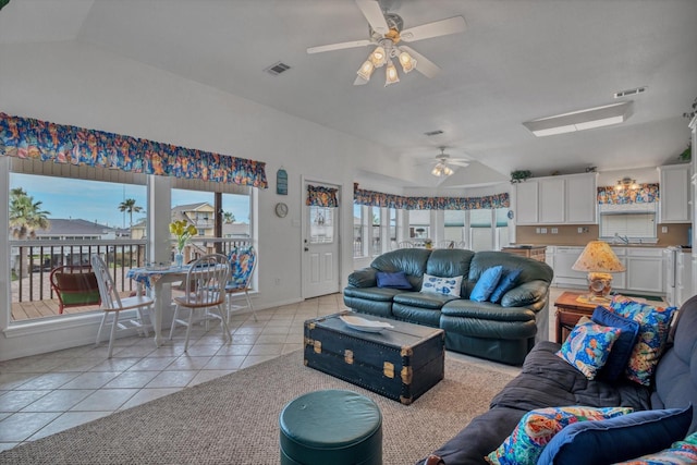 living area with a ceiling fan, light tile patterned floors, lofted ceiling, and baseboards