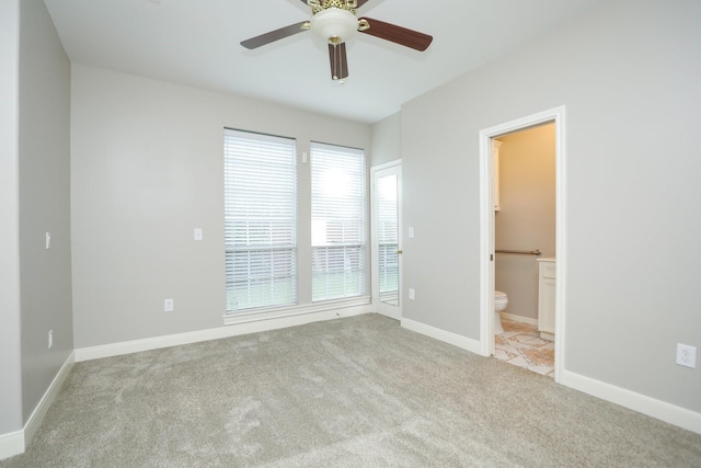 carpeted spare room featuring a ceiling fan and baseboards