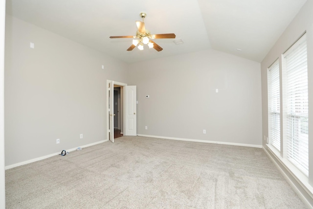 empty room featuring a ceiling fan, vaulted ceiling, healthy amount of natural light, carpet flooring, and baseboards
