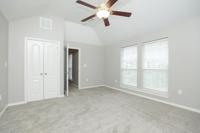 unfurnished bedroom featuring lofted ceiling, carpet, a closet, baseboards, and a ceiling fan