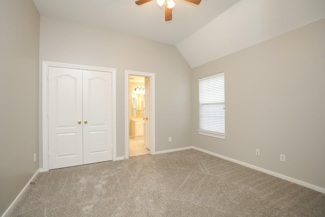 unfurnished bedroom featuring vaulted ceiling, carpet floors, a closet, baseboards, and connected bathroom