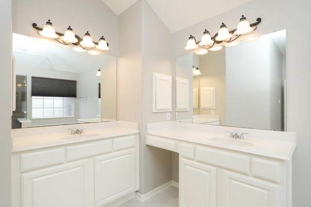 bathroom featuring two vanities, lofted ceiling, baseboards, and tile patterned floors