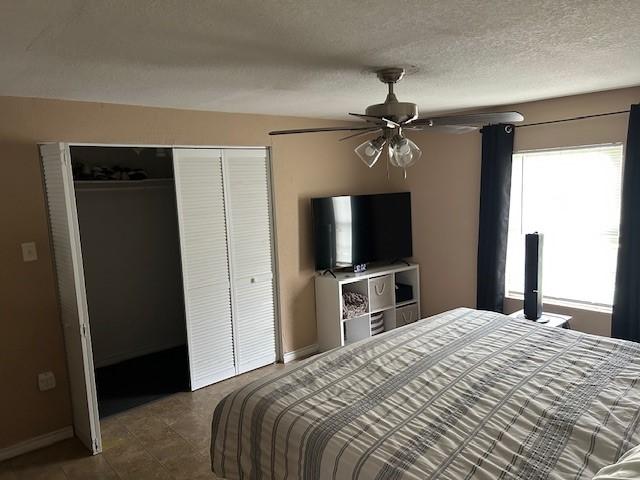 tiled bedroom featuring baseboards, a closet, a textured ceiling, and ceiling fan