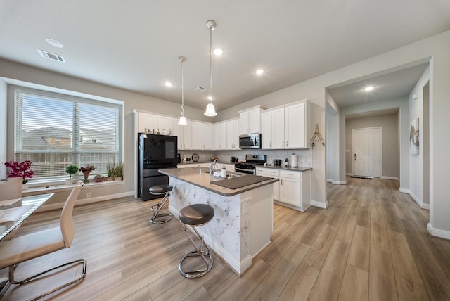 24323 Salts Mill Dr, Katy, TX 77493 - kitchen with stainless steel appliances, white cabinetry, light wood-style floors, an island with sink, and recessed lighting