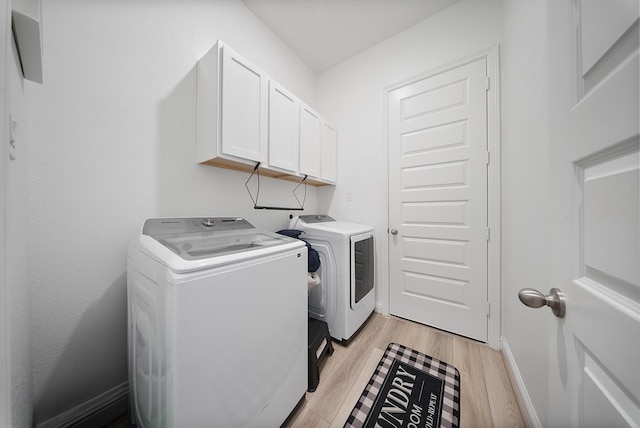 24323 Salts Mill Dr, Katy, TX 77493 - clothes washing area featuring washer and dryer, cabinet space, light wood-style flooring, and baseboards