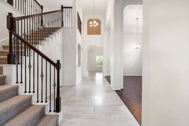 2107 Pearl Bay Ct, Pearland, TX 77584 - tiled entryway featuring arched walkways, a chandelier, stairs, a towering ceiling, and baseboards