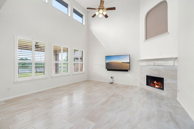 2107 Pearl Bay Ct, Pearland, TX 77584 - unfurnished living room featuring a tile fireplace, ceiling fan, a high ceiling, and baseboards