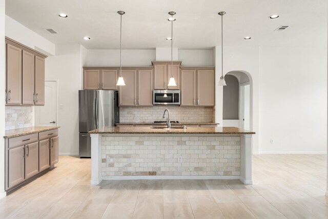 2107 Pearl Bay Ct, Pearland, TX 77584 - kitchen with appliances with stainless steel finishes, decorative backsplash, arched walkways, stone counters, and a sink