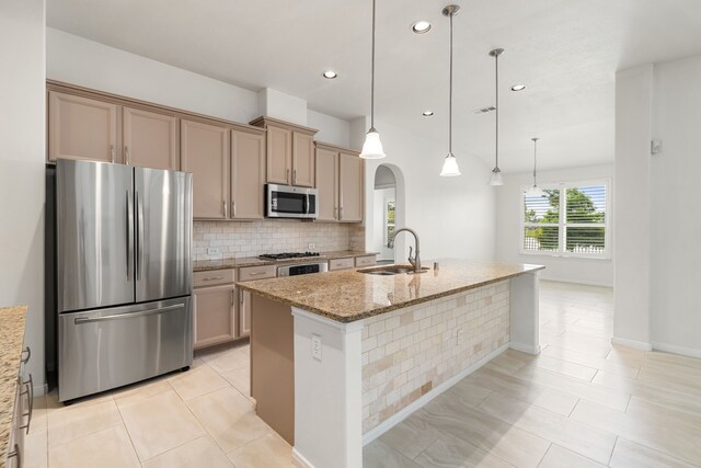 2107 Pearl Bay Ct, Pearland, TX 77584 - kitchen with appliances with stainless steel finishes, a sink, arched walkways, tasteful backsplash, and light stone countertops