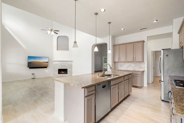 2107 Pearl Bay Ct, Pearland, TX 77584 - kitchen featuring a sink, stainless steel appliances, ceiling fan, arched walkways, and an island with sink