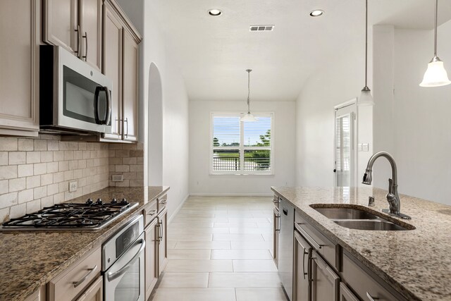 2107 Pearl Bay Ct, Pearland, TX 77584 - kitchen with appliances with stainless steel finishes, a sink, tasteful backsplash, arched walkways, and decorative light fixtures