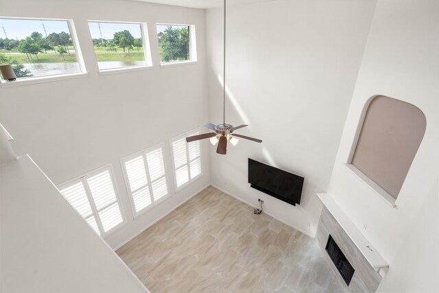 2107 Pearl Bay Ct, Pearland, TX 77584 - unfurnished living room with a ceiling fan, a tiled fireplace, and a high ceiling