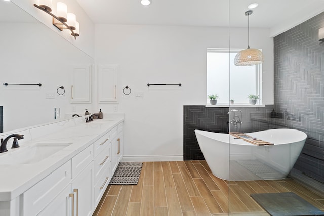 9603 Neon Moon Dr, Needville, TX 77461 - full bath featuring a freestanding tub, baseboards, double vanity, recessed lighting, and wood finished floors