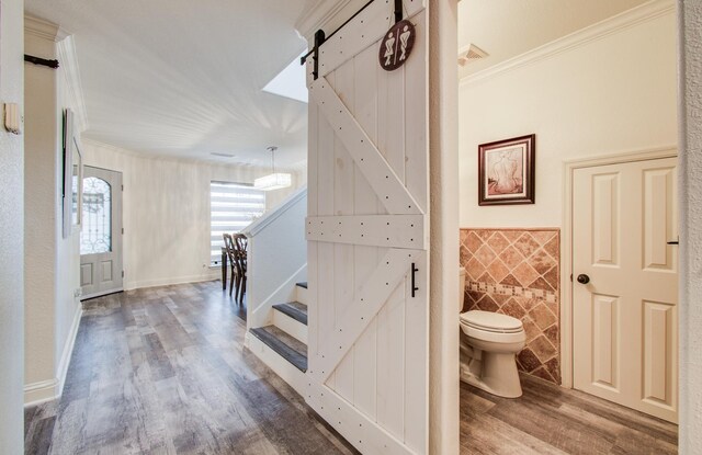 2519 Bradburn Hill Ln, Houston, TX 77014 - hallway with a barn door, wood finished floors, ornamental molding, tile walls, and stairs