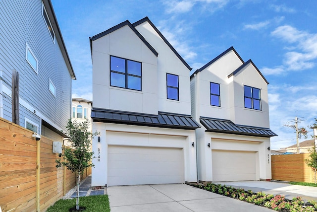 view of front facade featuring a standing seam roof, fence, an attached garage, stucco siding, and concrete driveway