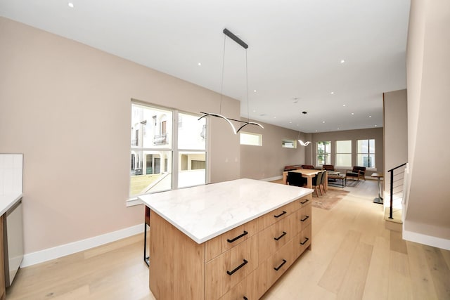 kitchen featuring modern cabinets, a kitchen island, light brown cabinetry, light wood-style flooring, and hanging light fixtures