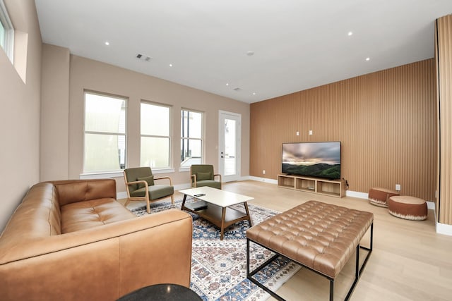 living area featuring light wood-style floors, an accent wall, baseboards, and recessed lighting