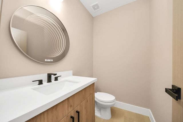 bathroom with toilet, vanity, and baseboards