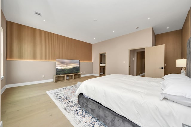 bedroom with light wood finished floors, an accent wall, and baseboards