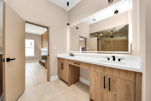 full bathroom featuring double vanity, a shower, and baseboards