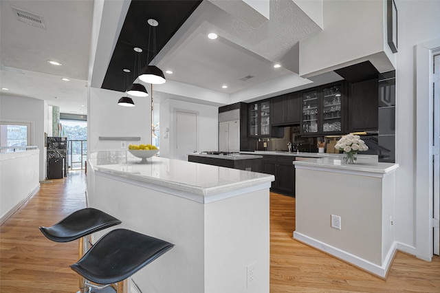 1804 N Memorial Way Unit B, Houston, TX 77007 - kitchen featuring light wood-style flooring, glass insert cabinets, a breakfast bar area, a peninsula, and recessed lighting