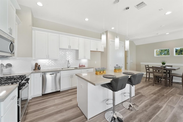 238 Julia St Unit E, Houston, TX 77022 - kitchen featuring stainless steel appliances, a sink, tasteful backsplash, light wood-style floors, and white cabinets