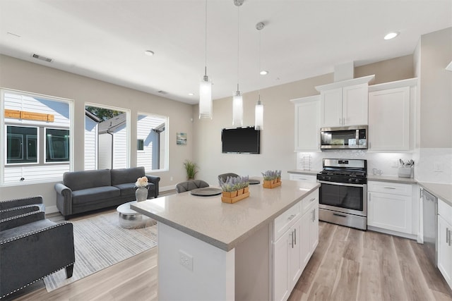 238 Julia St Unit E, Houston, TX 77022 - kitchen featuring stainless steel appliances, light wood-style flooring, open floor plan, backsplash, and white cabinetry