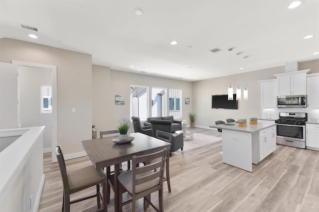 238 Julia St Unit E, Houston, TX 77022 - kitchen with appliances with stainless steel finishes, recessed lighting, white cabinets, light wood-type flooring, and a center island