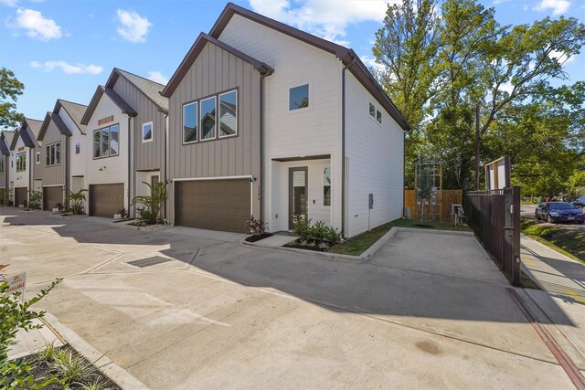 238 Julia St Unit E, Houston, TX 77022 - view of front facade featuring an attached garage, driveway, board and batten siding, and fence