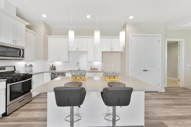 238 Julia St Unit E, Houston, TX 77022 - kitchen with stainless steel appliances, a sink, a kitchen island, white cabinets, and recessed lighting