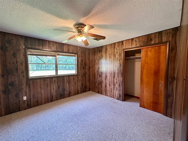 3605 Lawn Oak Dr, Orange, TX 77632 - unfurnished bedroom with wood walls, a closet, carpet flooring, a textured ceiling, and ceiling fan