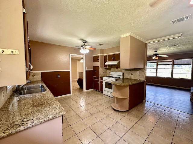 3605 Lawn Oak Dr, Orange, TX 77632 - kitchen with white gas stove, a ceiling fan, a sink, under cabinet range hood, and a textured ceiling