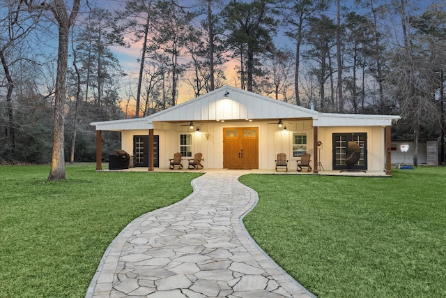 13537 Laramie Trl, Montgomery, TX 77316 - view of front facade with a ceiling fan, board and batten siding, a yard, and a patio area