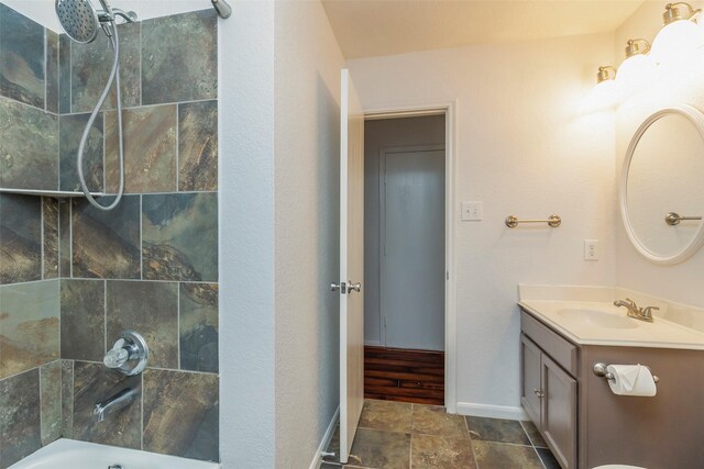 bathroom with vanity, baseboards, shower / bathtub combination, and stone finish flooring